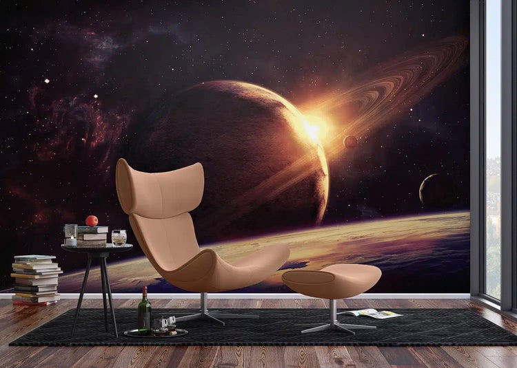 Fototapete mit Weltraum-Motiv, Planeten und Sternen in einem modern eingerichteten Wohnzimmer mit Sessel und Fußhocker.