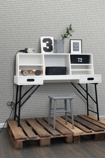 Szene mit einem Schreibtisch mit Aufsatzregal, einem Hocker und zwei Holzpaletten