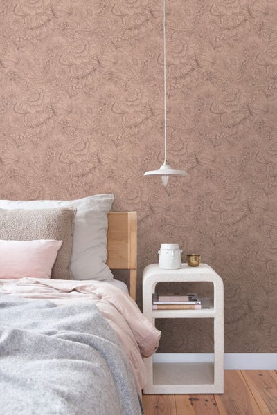 Schlafzimmer mit floral gemusterter Tapete, Holzbett mit Kissen und Decke, strukturiertem Nachttisch und einer Pendelleuchte.