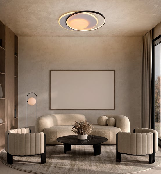 Wohnzimmer mit Sofa, Sesseln, Couchtisch, Deckenleuchte und leerem Bilderrahmen für die Wandgestaltung