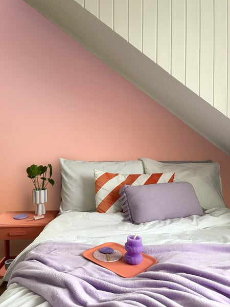 Schlafzimmer unter Dachschräge mit Bett, Kissen, Decke und Nachttisch