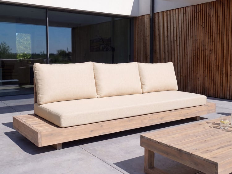 Modernes Gartensofa aus Holz mit beigen Polstern auf einer Steinterrasse vor einer Holzwand.