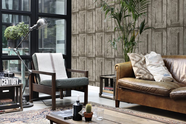 Wohnzimmer mit braunem Ledersofa, Sessel, Stehlampe und gemusterter Tapete in Holzoptik