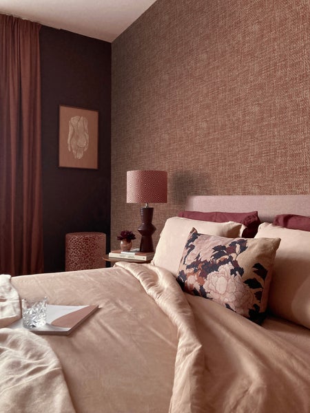 Schlafzimmer mit Bett, Kissen, Nachttischlampe und dekorativen Elementen für eine gemütliche Atmosphäre