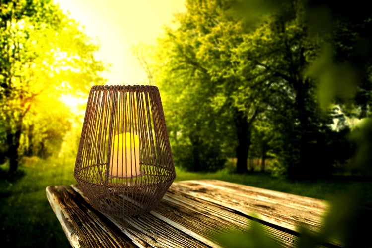 Dekorative Laterne mit Kerze auf einem Holztisch im Freien