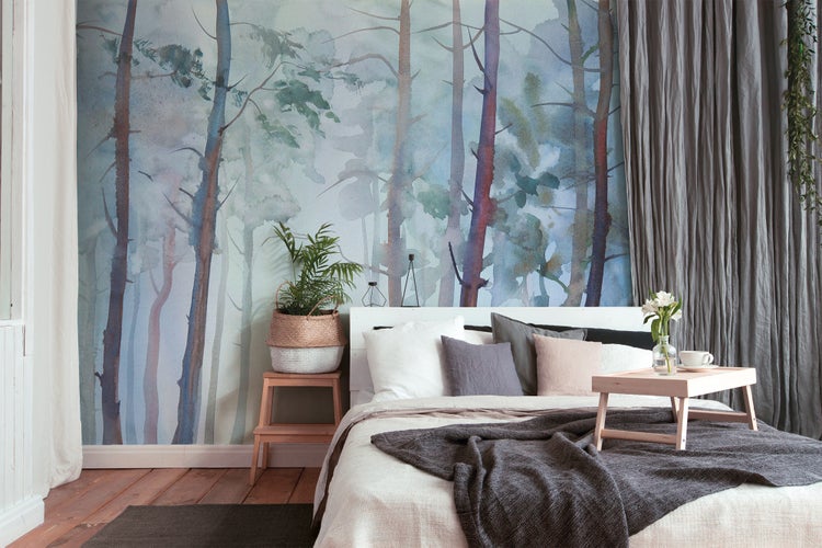 Fototapete mit Waldmotiv im Aquarellstil hinter einem Bett im Schlafzimmer, moderne Wandgestaltung mit Bäumen und Vorhängen.
