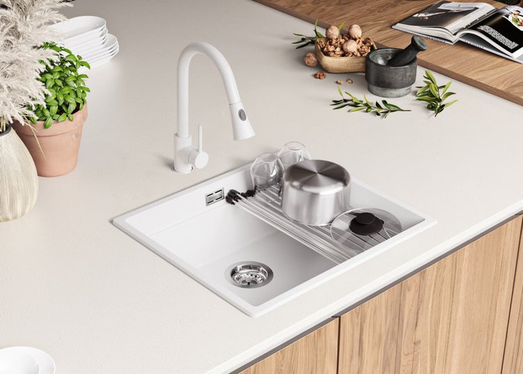 Küchenspüle mit Abtropfgestell, Wasserhahn und Küchenutensilien auf einer Arbeitsplatte