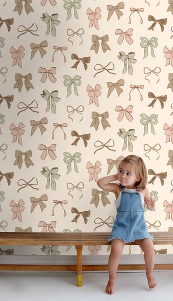 Mädchen vor einer Wand mit Schleifenmuster auf einer Holzbank