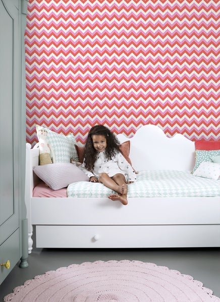 Kinderzimmer mit Zickzacktapete, weißem Bett und rundem Teppich