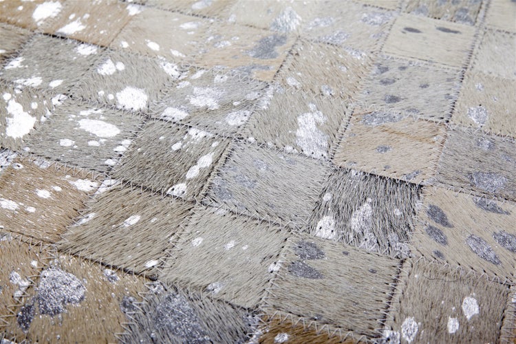 Patchwork-Teppich aus Kuhfell-Quadraten mit silbernen Metallic-Akzenten und Zickzack-Nähten.