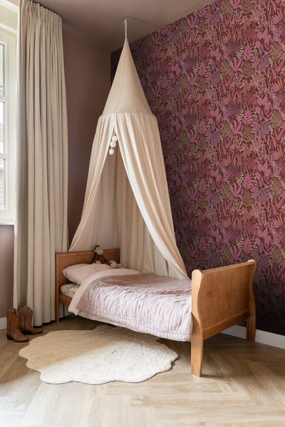Kinderzimmer mit Himmelbett, gemusterten Tapeten und Teppich