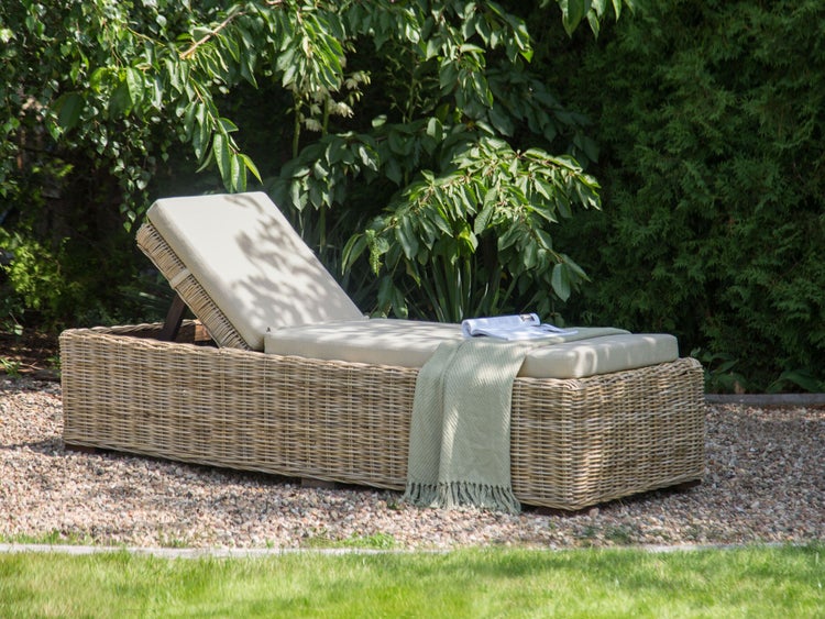Gartenszene mit Liege aus Rattan mit Auflage, Decke und Zeitschrift