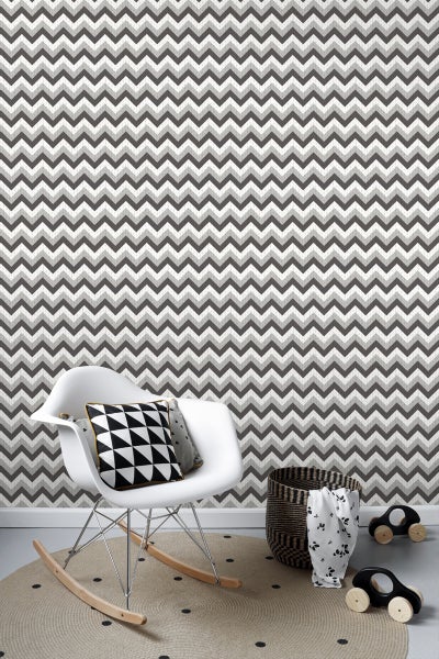 Zimmeransicht mit Zickzacktapete, Schaukelstuhl und rundem Teppich