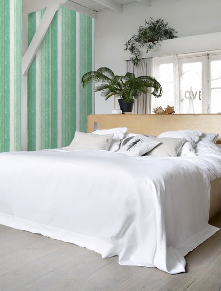 Schlafzimmer mit Bett, Kissen und Pflanzen