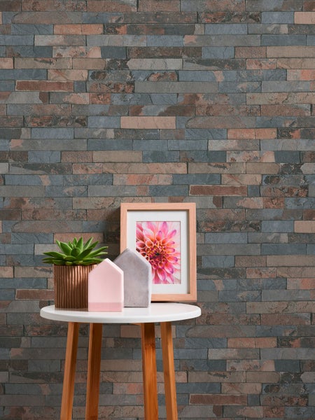 Raumansicht mit gemusterter Tapete, Kerzenständer, Hocker und Pflanzgefäßen