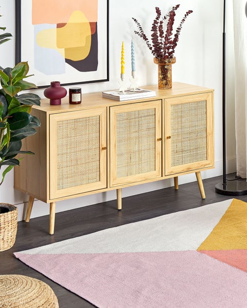 Modernes Sideboard aus hellem Holz mit drei Türen und Rattangeflecht, dekoriert mit Vasen auf einem geometrischen Teppich in einem hellen Wohnzimmer.