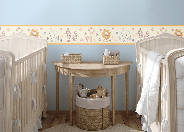 Tapetenbordüre mit Safari-Tieren wie Elefant, Löwe, Giraffe und Affe in einem hellen Kinderzimmer mit Gitterbetten und Holztisch.
