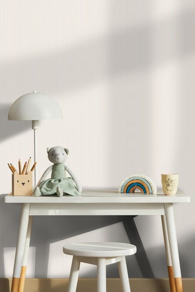 Gestreifte Tapete im hellen Kinderzimmer hinter einem Schreibtisch mit Lampe und Spielzeug.