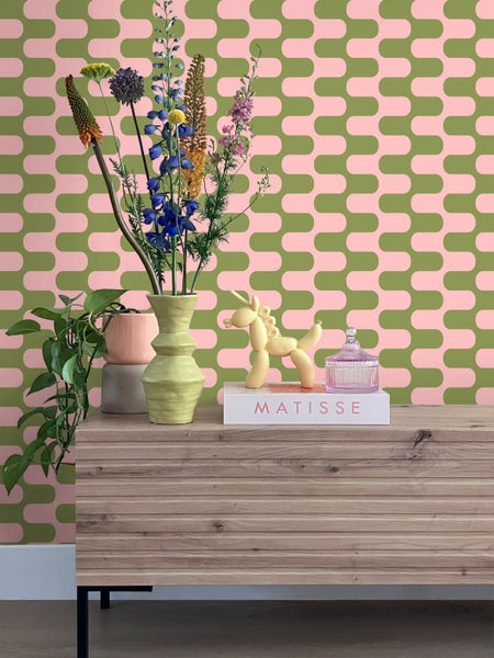 Dekoratives Stillleben mit Vase, Blumen und geometrischer Tapete im Hintergrund