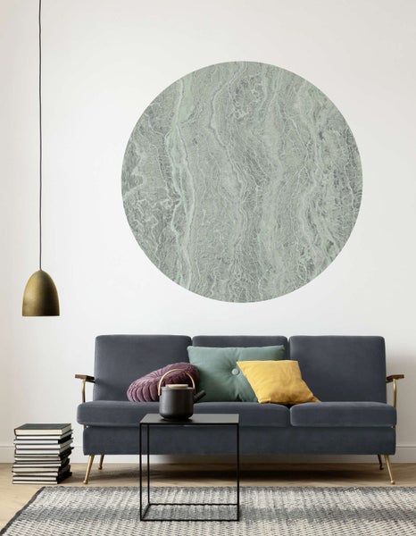 Wohnzimmer mit Sofa, Kissen, Tisch, Stapel Bücher, Teppich und einem Wandbild