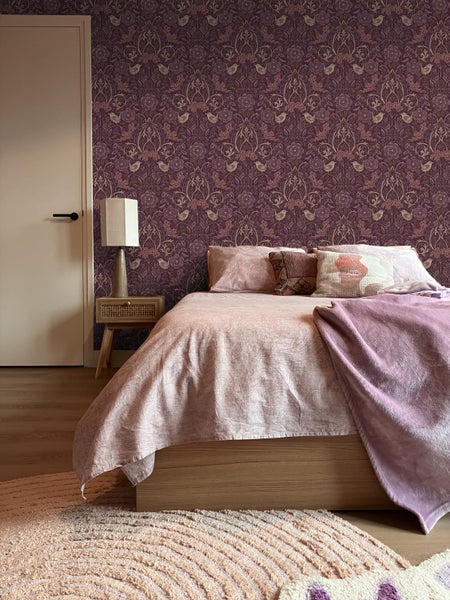 Schlafzimmer mit Bett, Nachttisch und gemusterter Tapete