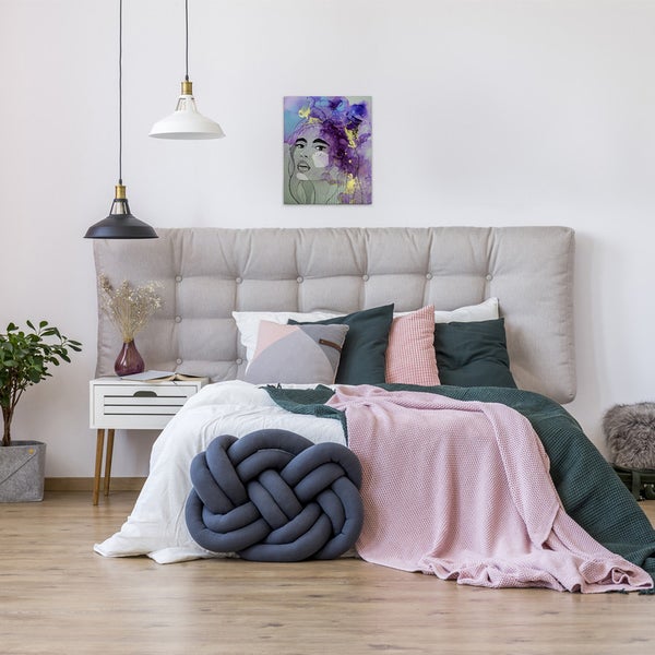 Schlafzimmer mit Bett, Kissen und einem Wandbild mit einem Frauenporträt.