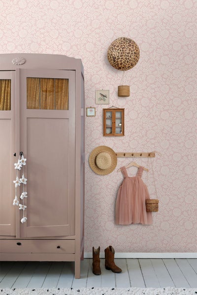 Vliestapete mit floralem Muster in Rosa und Weiß in einem Kinderzimmer mit rosa Schrank, Kleiderhaken und Dekoration.