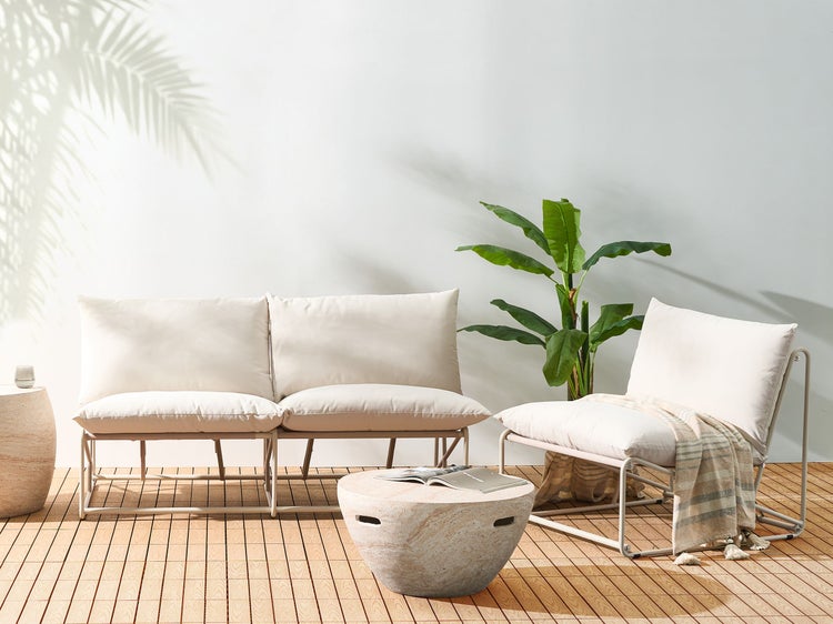 Helle Gartenszene mit einem Sofa, einem Sessel, einem Tisch und einer Pflanze für eine entspannte Atmosphäre im Freien.