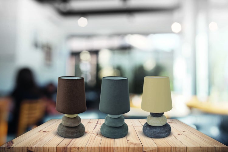 Drei Tischlampen mit Stoffschirm und Steinfuß auf einem Holztisch
