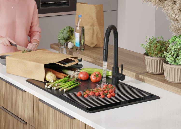 Küchenszene mit Spüle, Armatur, Gemüse und Person beim Kochen