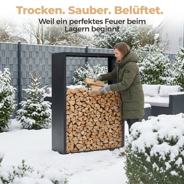 Eine Frau lagert Holz in einem schwarzen Kaminholzregal im verschneiten Garten.
