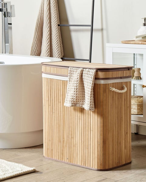 Rechteckiger Wäschekorb aus Bambus mit Deckel und Seilgriffen in einem hellen Badezimmer neben einer weißen Badewanne.