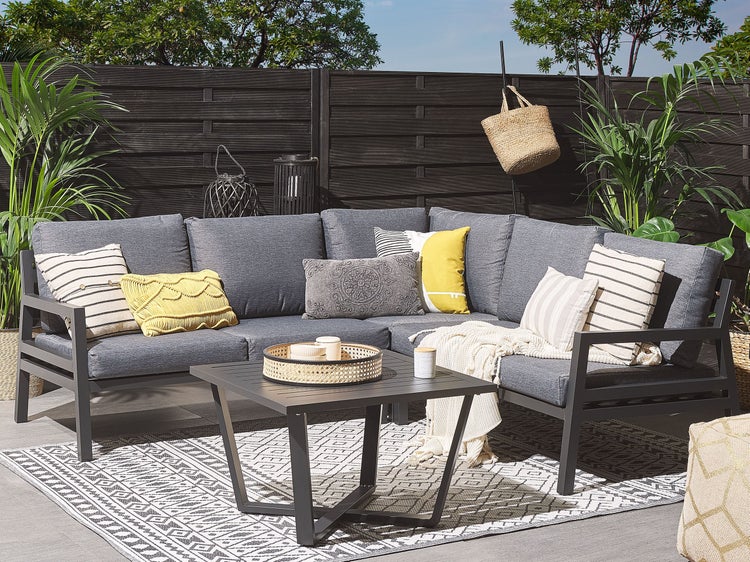 Gartenszene mit Ecksofa, Kaffeetisch und Outdoor-Teppich auf einer Terrasse