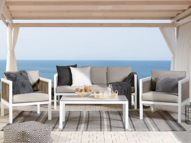 Terrasse mit Sofa, Sesseln, Tisch und Teppich vor dem Meer