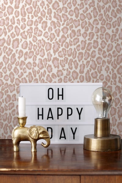 Dekorative Szene mit Tapete im Leopardenmuster, Leuchtkasten, Kerzenständer in Elefantenform und Lampe.