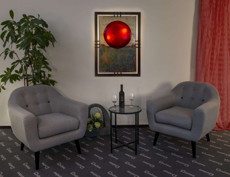 Zwei graue Sessel mit Knopfdesign und ein Beistelltisch mit einer Flasche Wein und Gläsern in einem Wohnzimmer.