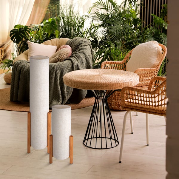 Wohnzimmer mit zwei Stehlampen, Korbstühlen, Korbtisch und vielen Pflanzen