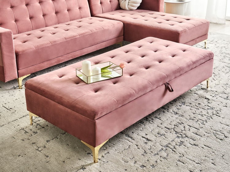 Rosa Ottoman mit Stauraum und goldenen Füßen neben rosa Sofa auf gemustertem Teppich