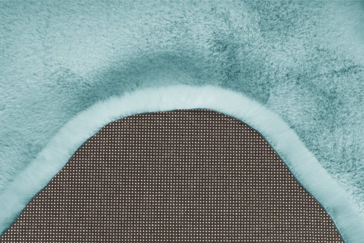Hellblauer Kunstfell Teppich mit weicher Oberfläche und rutschfester Unterseite mit Noppen.