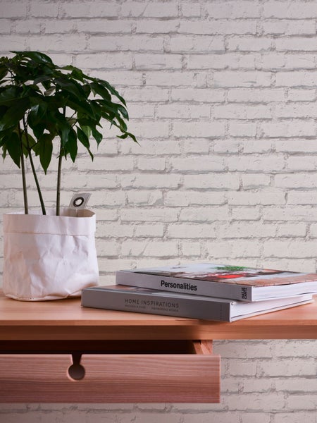 Schreibtisch mit Lampe, Stuhl und Wanddekoration in einem hellen Raum.