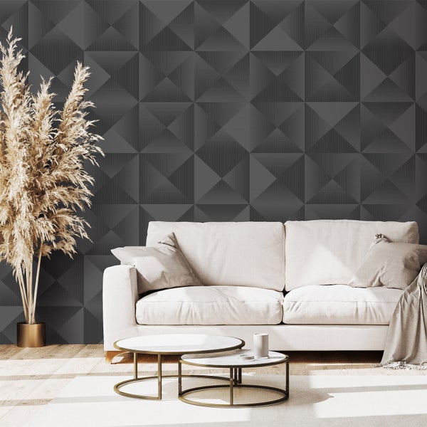 Modernes Wohnzimmer mit dunkler geometrischer Tapete in dreidimensionaler Optik, hellem Sofa, Satztischen aus Metall und Marmor und Ziergraspflanze.
