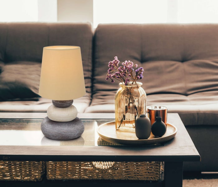 Dekorative Tischlampe mit Stoffschirm und Steinfuß auf einem Wohnzimmertisch.