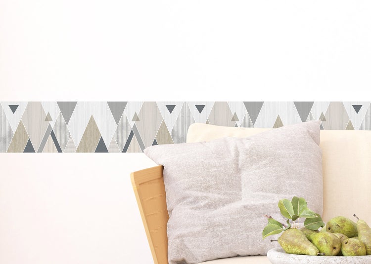 Selbstklebende Wandbordüre mit geometrischem Dreiecksmuster in Holzoptik und Grautönen in einem hellen Wohnzimmer.
