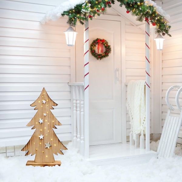 Weihnachtliche Veranda-Dekoration mit Holzbaum, Girlande und Schlitten.