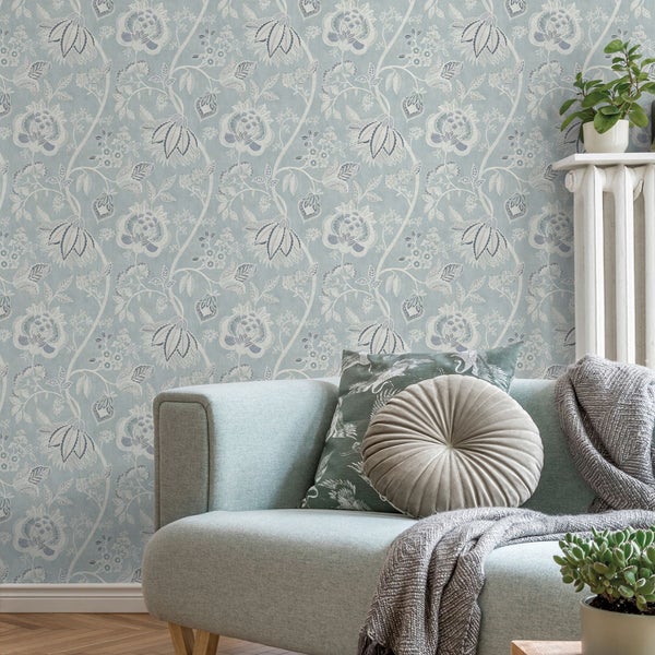 Wohnzimmer mit floral gemusterter Tapete, Sofa und Zimmerpflanzen für eine gemütliche Atmosphäre