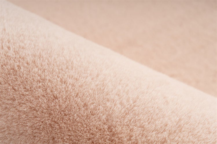 Nahaufnahme der Textur eines beigen Hochflor-Teppichs.