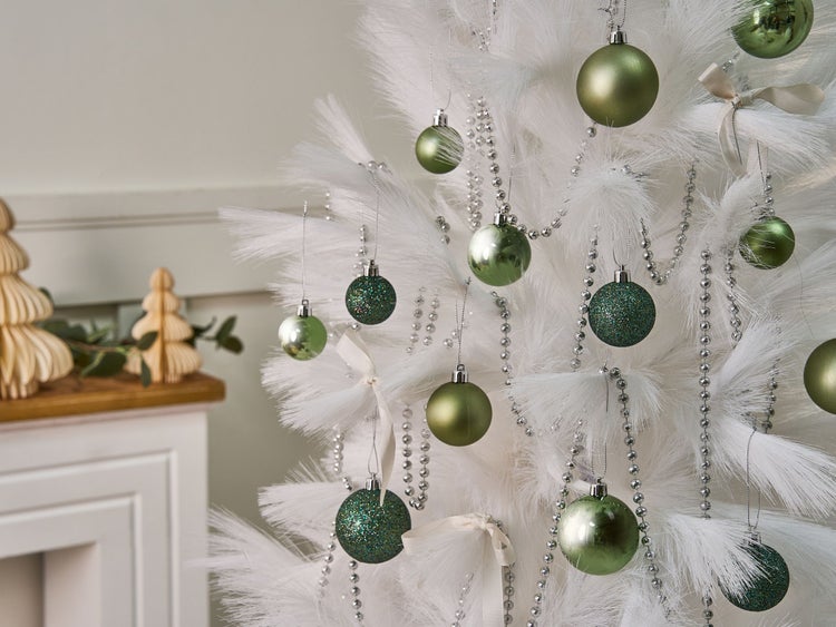 Weihnachtsszene mit einem weißen Baum geschmückt mit grünen Kugeln und silberner Perlenkette