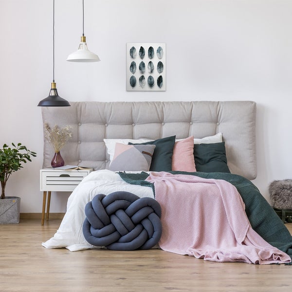 Schlafzimmer mit Bett, Kissen, Decken, Nachttisch, Lampen und Wandbild