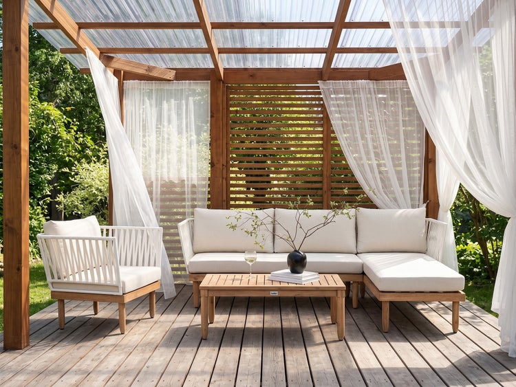 Moderner Garten-Loungebereich auf Holzterrasse unter einer Pergola mit weißen Polstermöbeln, Holztisch und hellen Vorhängen.