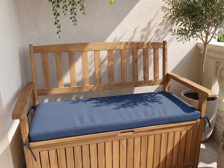 Gartenbank aus Holz mit Stauraum, Rückenlehne und blauem Sitzkissen auf einem Balkon.